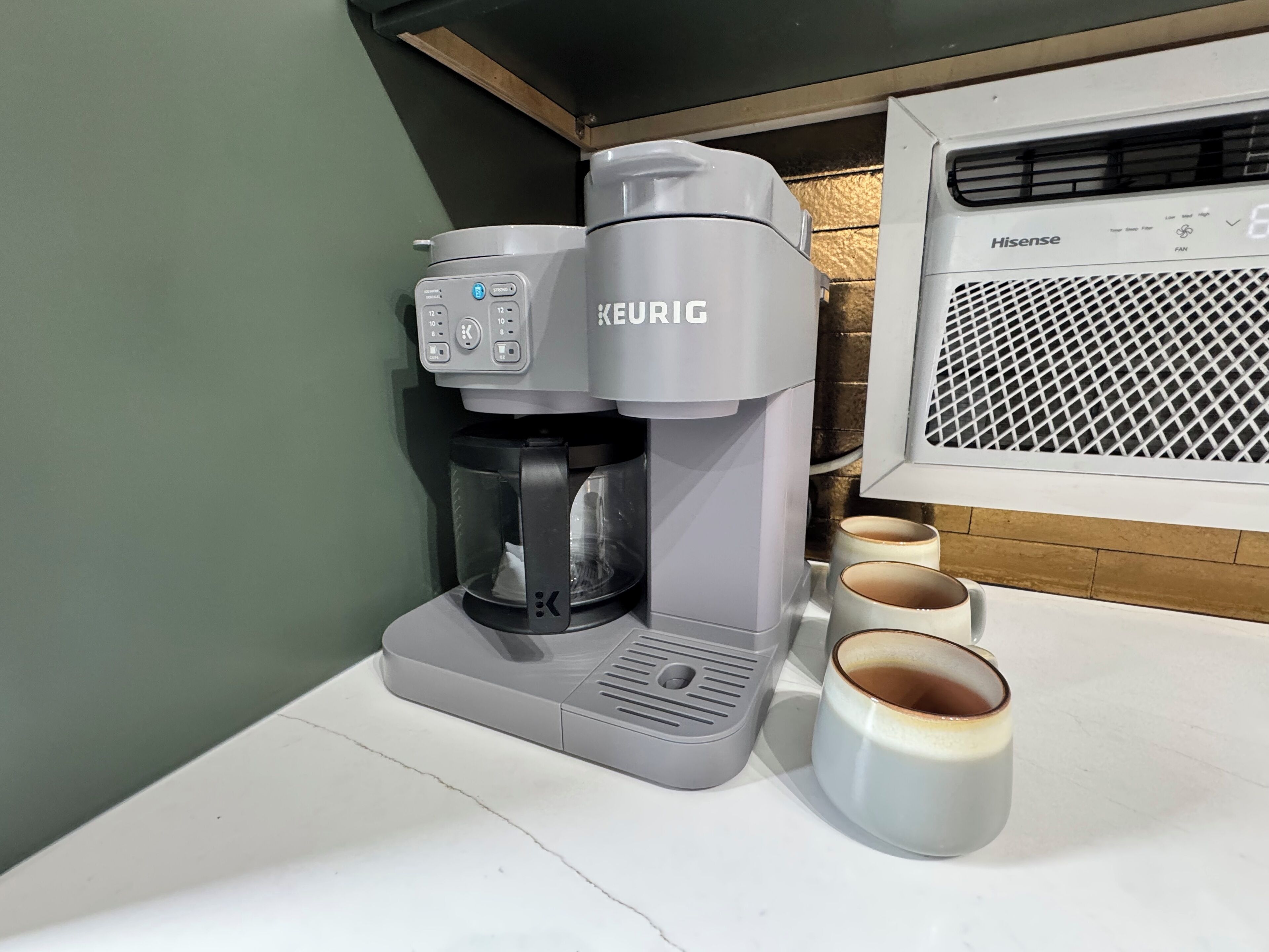 Une machine à café Keurig, un purificateur d’air Hisense à côté, et deux tasses sur le comptoir.