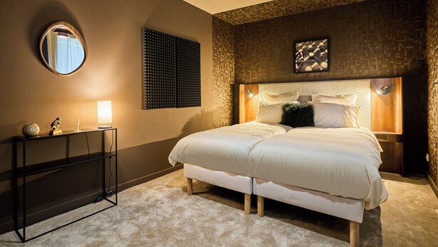 A bedroom with a large bed, a bedside table, a mirror, and a wall-mounted light fixture. - Paillettes fever, house with karaoke, 3 bedrooms (Croix)