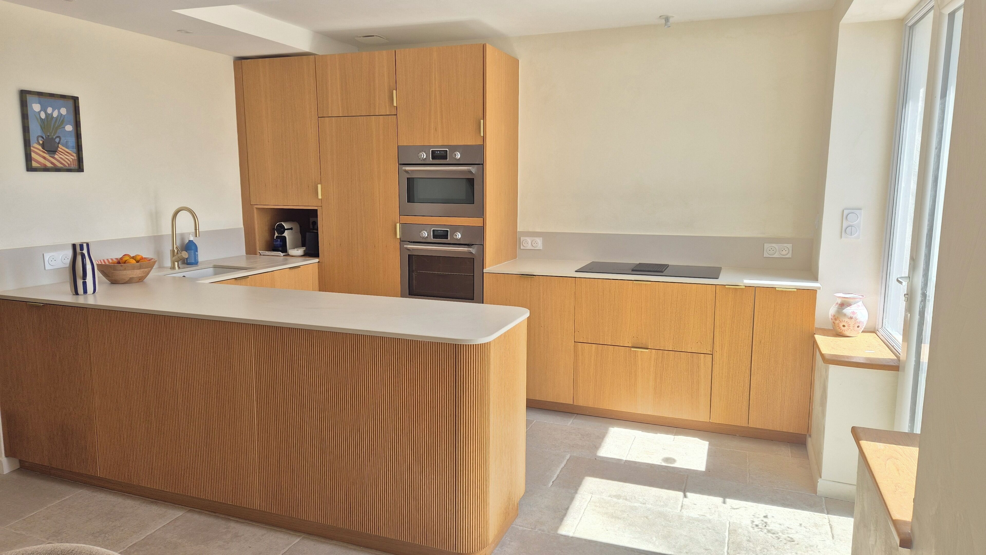 Une cuisine moderne avec des meubles en bois, un îlot central et des appareils électroménagers intégrés.