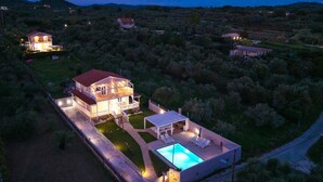 Ein zweistöckiges Haus mit Schwimmbecken und einer überdachten Terrasse.