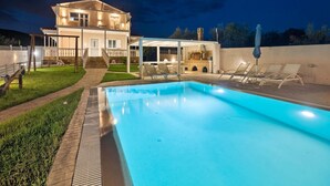 Ein zweistöckiges Haus mit Swimmingpool, Sitzgelegenheiten im Freien und einer Grillzone.