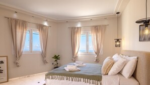 Ein Schlafzimmer mit einem Bett, Vorhängen, einer Pflanze und einem gerahmten Bild an der Wand.