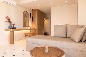 Un salon moderne comprenant un canapé, une table d’appoint en bois, un fauteuil et une petite table sur laquelle est posé un objet décoratif.