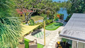 Un jardín con un tablero de ajedrez, una piscina y una casa de techo rojo.