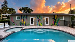 Un espace piscine agrémenté d’une fresque murale, une piscine et un bâtiment doté de portes et de fenêtres.