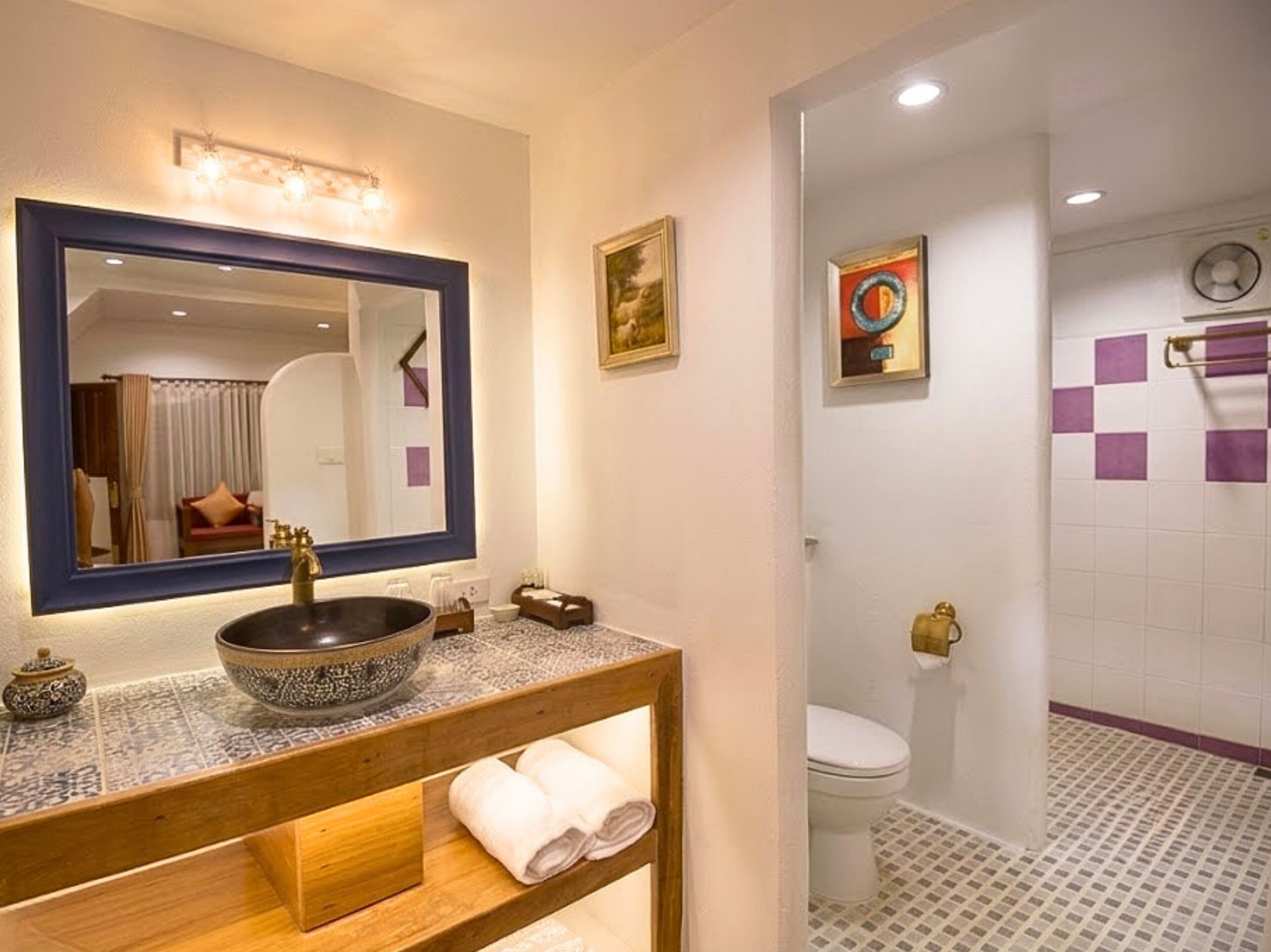 Un baño con un espejo grande, un lavabo, un inodoro y una zona de ducha.