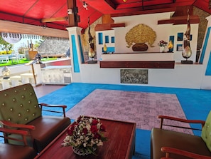 A spacious outdoor seating area with a blue carpet, wooden furniture, and a decorative wall with artwork. - The Moon Rabbit Resort Pai (Pai)