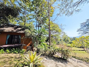 A rustic building with a sloped roof, surrounded by lush greenery and a clear sky. - The Moon Rabbit Resort Pai (Pai)