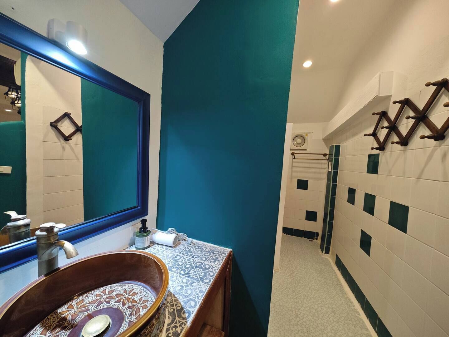 A bathroom with a large mirror, a sink with a decorative basin, and a towel rack.