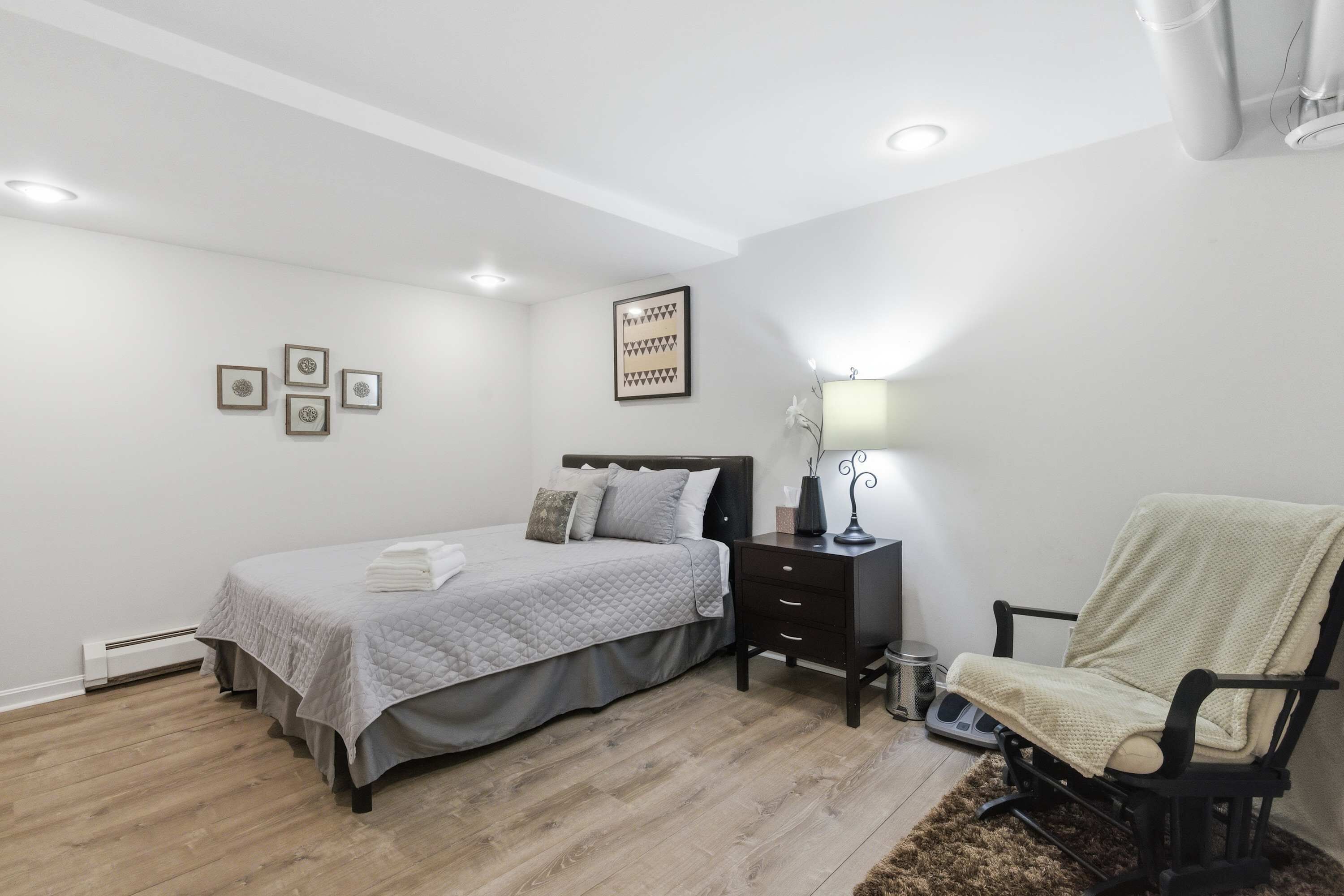 A bedroom with a bed, bedside table, chair, and wall decorations.