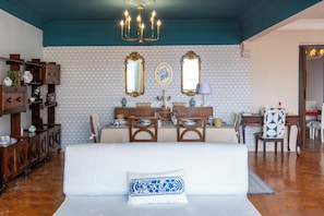 A room with a sofa, a dining table, chairs, a chandelier, and a mirror. - Zamalek suuny khan (Cairo Governorate)