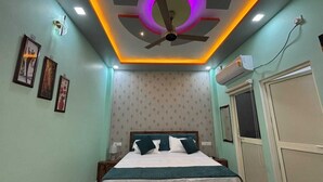 Un dormitorio con cama, ventilador de techo, aire acondicionado instalado en la pared y cuadros enmarcados.