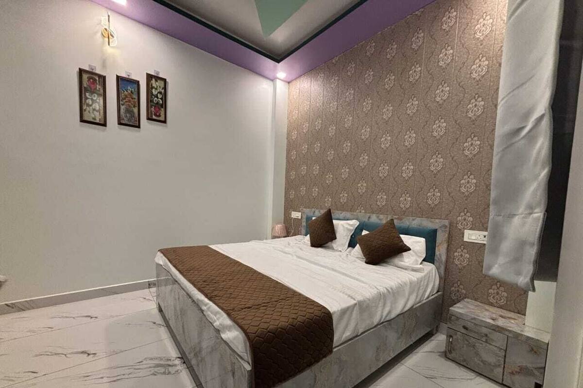 A bedroom with a bed, nightstands, and a wall with framed pictures.