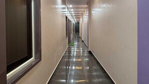 Un pasillo largo y estrecho con suelo de baldosas negras brillantes y paredes de tonos claros.
