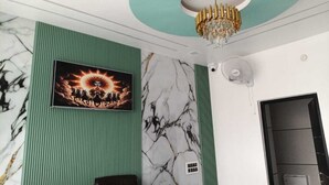 Una habitación con pared verde, pared con diseño de mármol, una araña y un cuadro enmarcado.