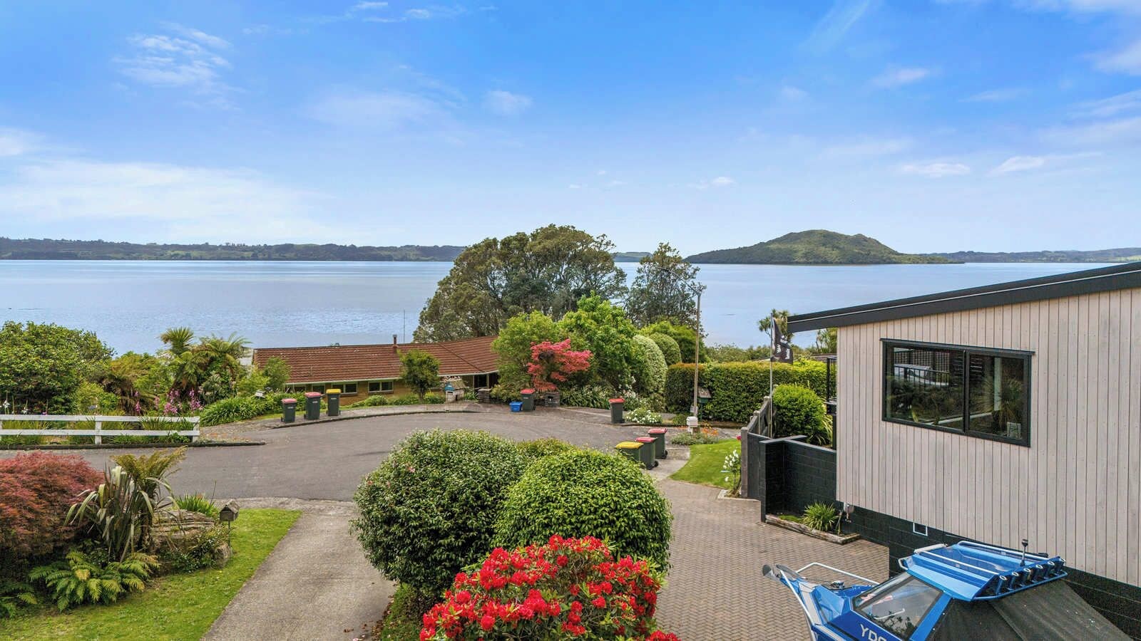A residential property with a view of a lake, a fenced yard, and a building with a large window.