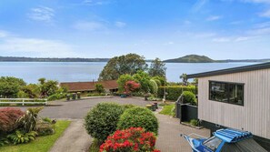 A residential property with a view of a lake, a fenced yard, and a building with a large window. - Inn Manahi - Lake Views, Cosy Retreat for 2 (Rotorua)