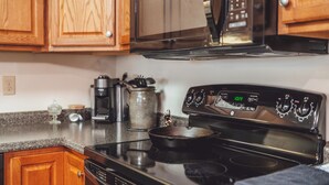 Una cocina con armarios de madera, una estufa negra y un microondas.