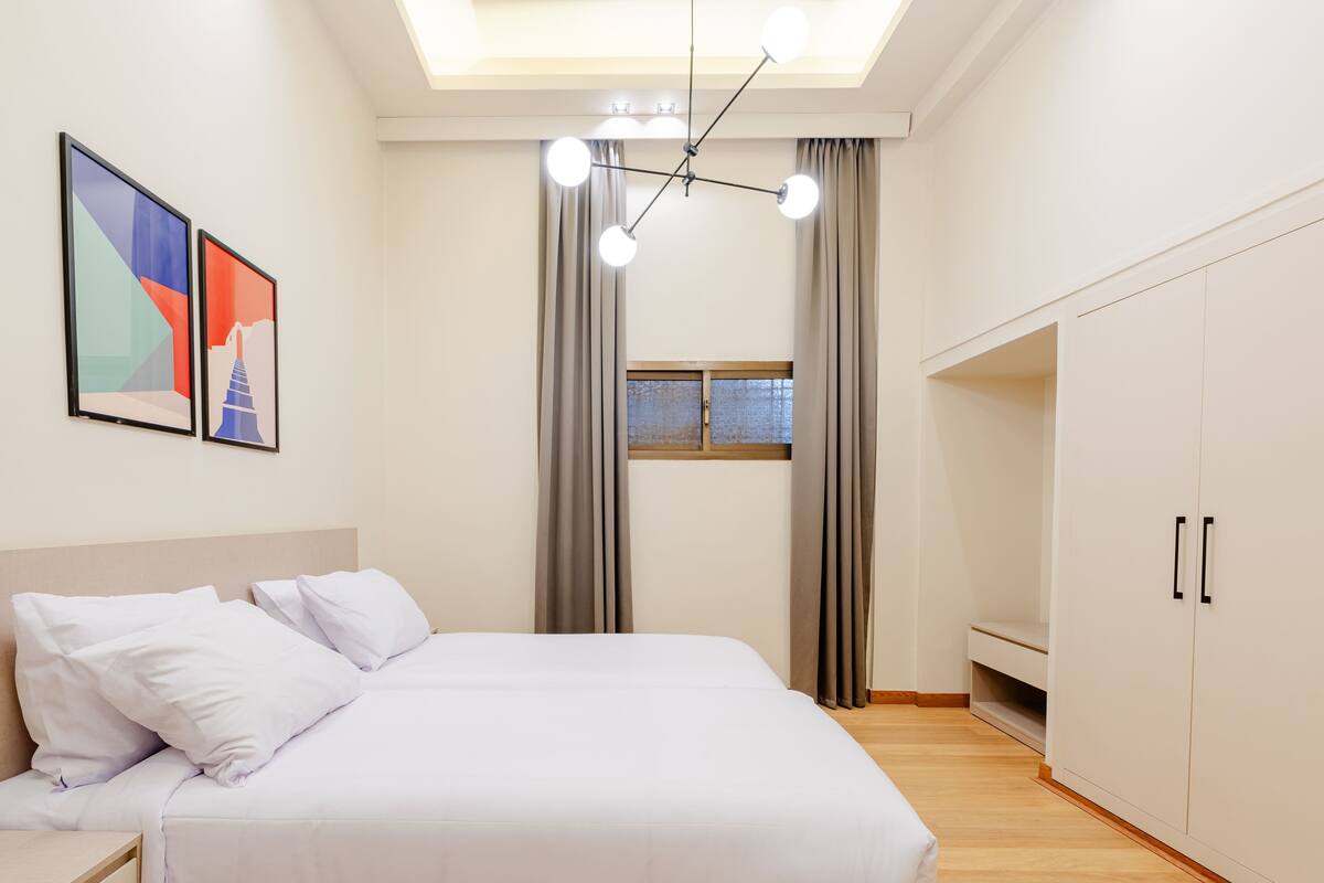 Un dormitorio con cama, mesita de noche, armario y tragaluz.