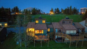 Un barrio residencial con casas que tienen balcones y zonas de estar al aire libre, rodeado de árboles y un paisaje montañoso.