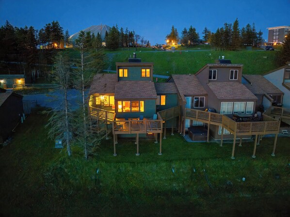 Un quartier résidentiel où les maisons sont dotées de balcons et d’espaces extérieurs aménagés, le tout entouré d’arbres et d’un paysage vallonné.