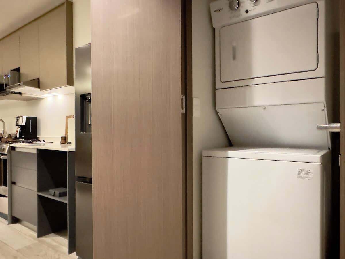 A compact kitchen with a built-in washer and dryer, a coffee machine, and a microwave.