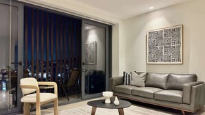 A modern living room with a sofa, a chair, a coffee table, and a large abstract artwork on the wall. - Plaza Peninsula TJ Zona Dorada 3era Etapa Rio (Tijuana)