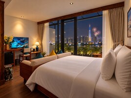 Habitación de hotel con una cama grande, televisión, escritorio y vista al horizonte de la ciudad de noche.
