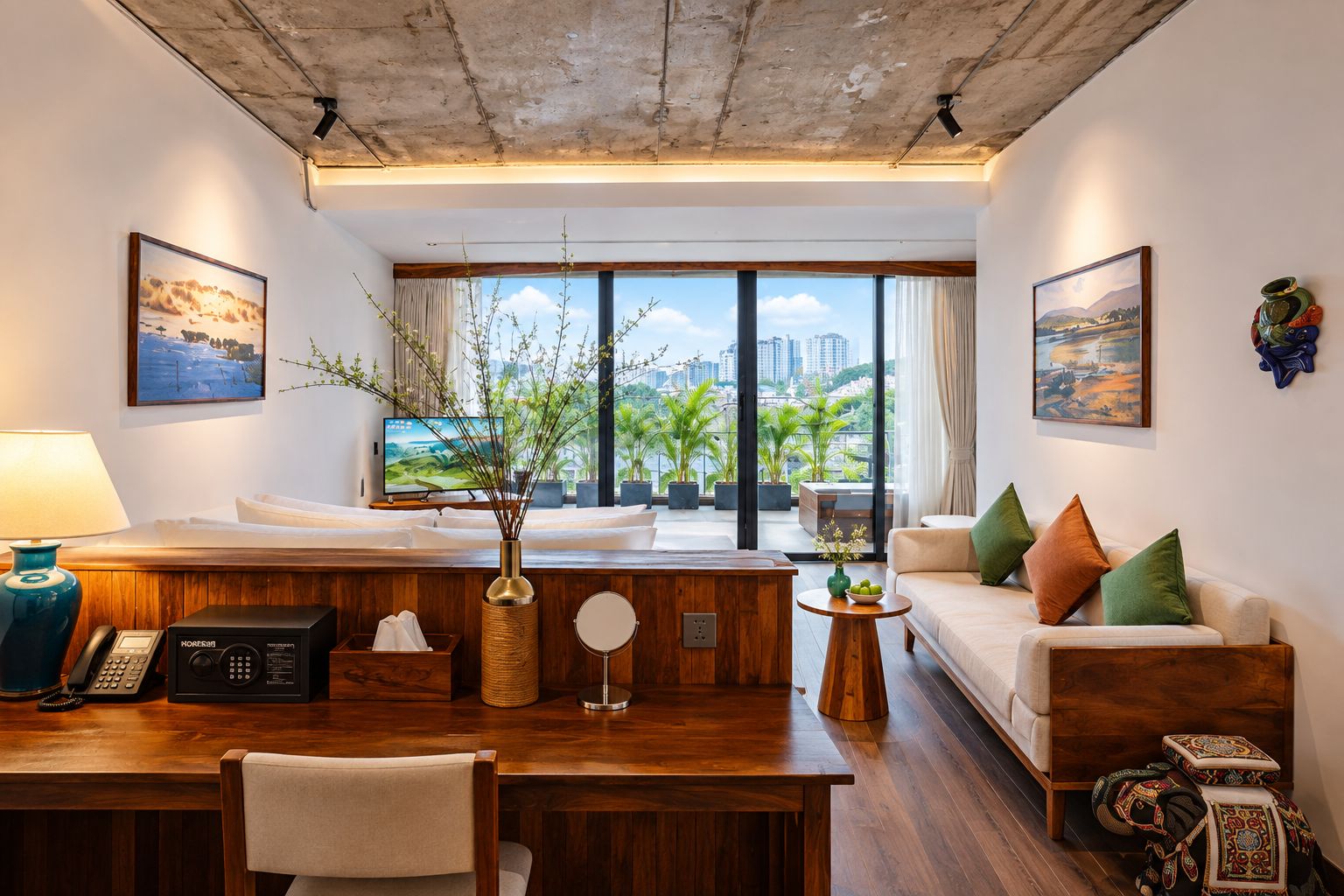 Habitación de hotel moderna con un escritorio de madera, un sofá, un televisor y un balcón con vistas a la ciudad.