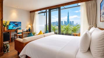Quarto de hotel com uma cama grande, uma mesa de trabalho e uma televisão, e vista para o horizonte da cidade.