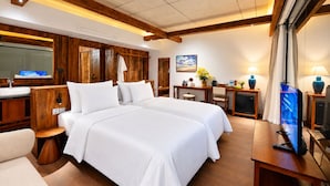 Ein Hotelzimmer mit einem großen Bett, Holzmöbeln, einem Schreibtisch mit Computer und einem Fernseher.