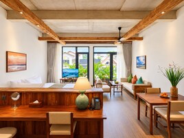 Habitación de hotel con escritorio de madera, sofá, mesa de comedor y vistas al exterior.