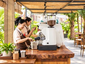 A coffee shop with a coffee machine and a grinder, and two baristas working. - Nexus House Retreat Xuan Thuy (Ho Chi Minh City)
