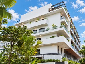 A multi-story hotel with balconies, large windows, and lush greenery.