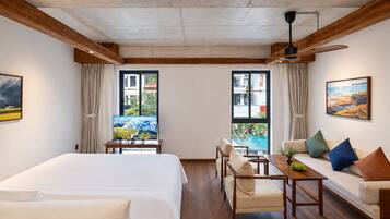 A hotel room with a bed, a sofa, a table, and two windows with curtains.