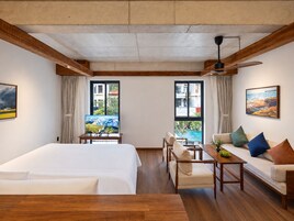 Una habitación de hotel con cama, sofá, mesa y dos ventanas con cortinas.