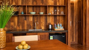 Eine Küche mit Holzschnitzereien, einem Spülbecken, einem Kühlschrank und einem Esstisch mit einer Fruchtschale.
