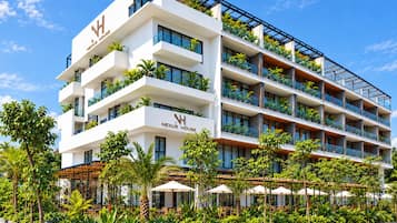 A multi-story hotel with balconies, outdoor seating, and lush landscaping.
