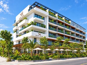 Un hôtel à plusieurs étages doté de balcons, d’un espace extérieur aménagé pour s’asseoir et d’une végétation luxuriante.