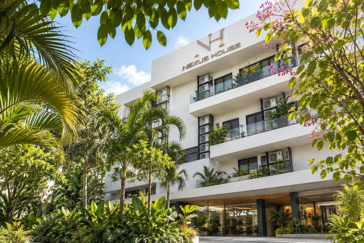 A multi-story hotel with a modern design, featuring balconies with plants, and surrounded by lush greenery.