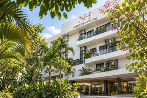 A multi-story hotel with a modern design, featuring balconies with plants, and surrounded by lush greenery.