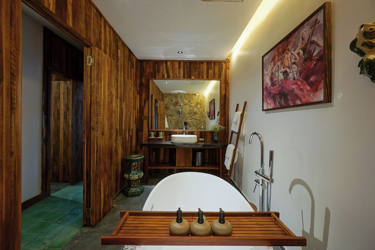 A bathroom with a wooden vanity, a bathtub, and a large mirror.