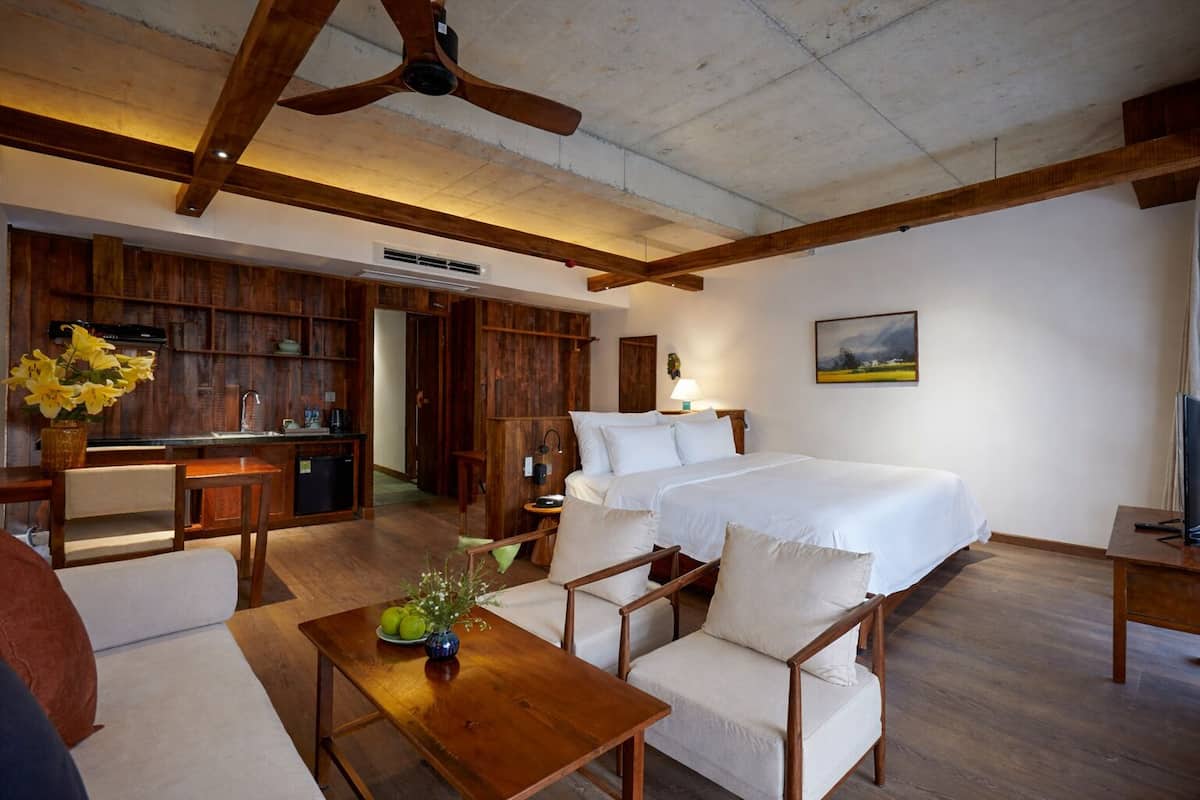 A room with a bed, a desk, a chair, a table, and a ceiling fan.
