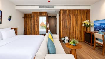 A hotel room with a large bed, a sofa, a desk, and a television.