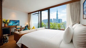 A modern hotel room with a large bed, a desk with a computer, and a view of a city skyline. - Nexus House Retreat Xuan Thuy (Ho Chi Minh City)