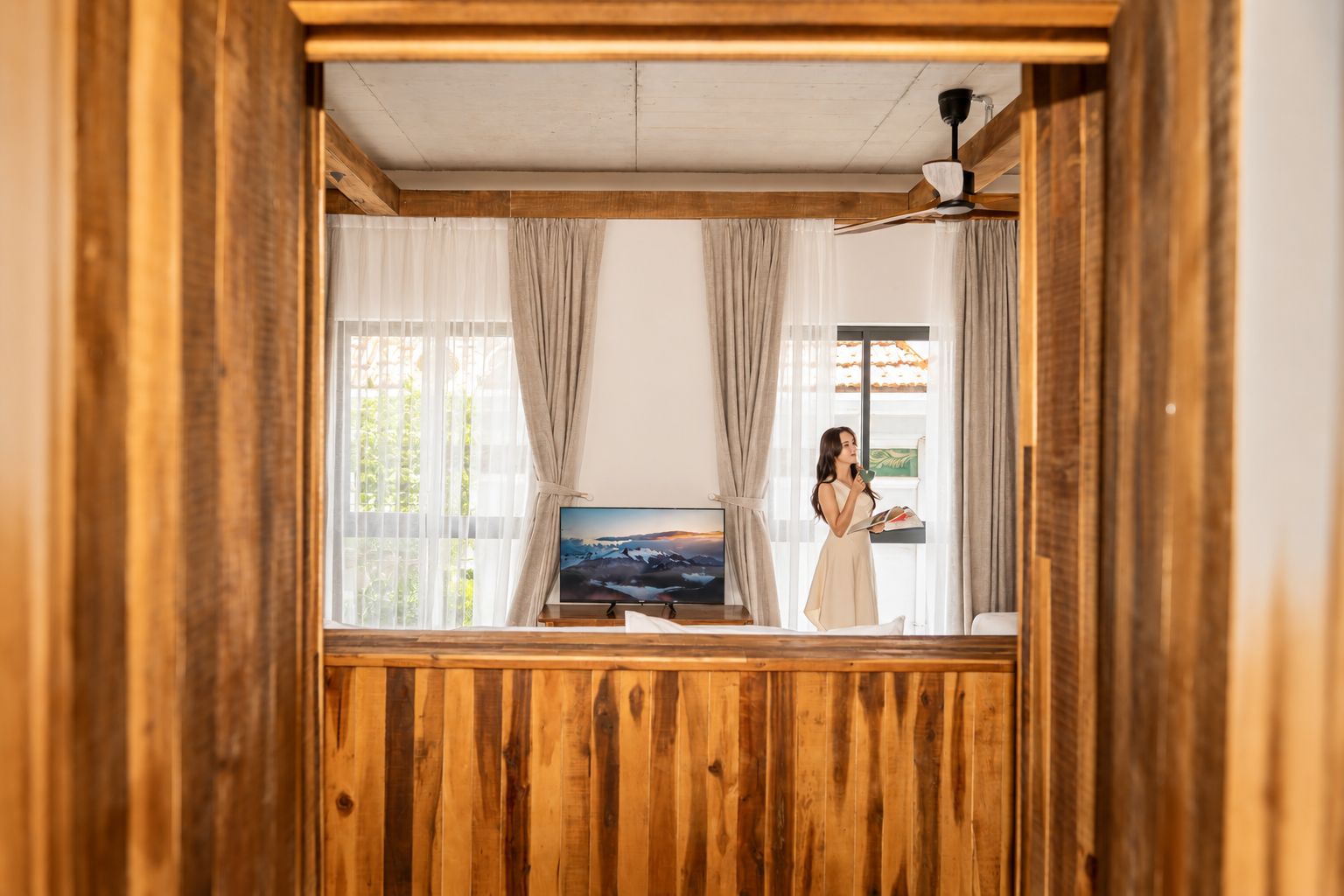 Una habitación con paneles de madera, un televisor y una ventana con cortinas.