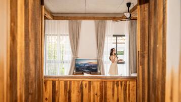Una habitación con paneles de madera, un televisor y una ventana con cortinas.