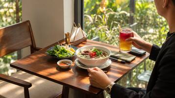 A dining table with a bowl of soup, a plate of vegetables, and a glass of beverage.