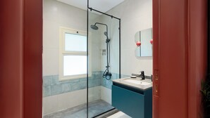 Ein modernes Badezimmer mit Duschkabine aus Glas, Waschbecken und Spiegel.