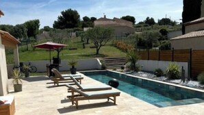 Zona de piscina con sillas de descanso y una parrilla.